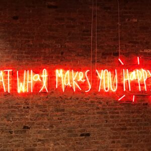 Red neon lighting that says eat what makes your happy