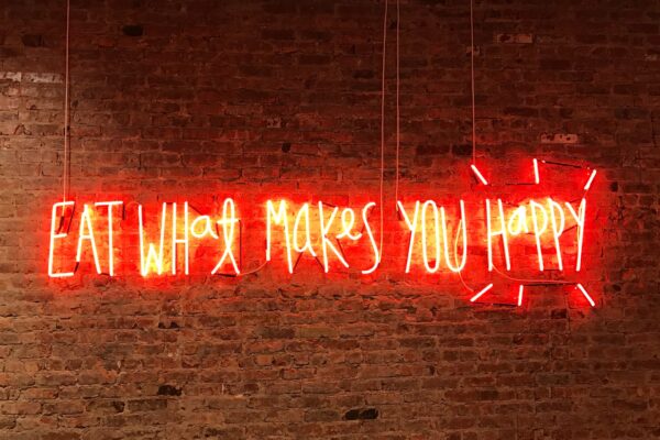 Red neon lighting that says eat what makes your happy