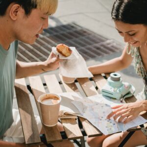 Couple drinking coffee and eating snacks whilst planning their route on a paper map