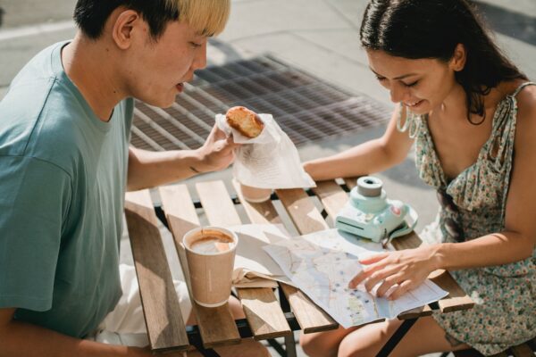 Couple drinking coffee and eating snacks whilst planning their route on a paper map