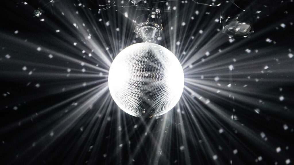 Black and white image of a glitter ball, reflecting light into the darkness.